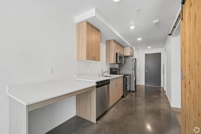 Modern kitchen design with sleek stainless steel appliances, elegant wooden cabinets, and a glossy countertop in a bright, spacious area.