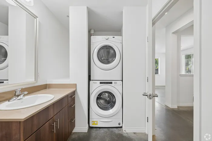 Modern bathroom with sleek wood cabinetry and in-unit stacked washer and dryer, providing stylish and convenient living.