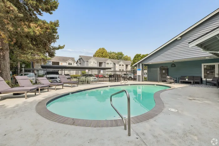 Inviting outdoor swimming pool area with comfortable lounge chairs and modern seating, perfect for relaxation and leisure in a serene residential setting.