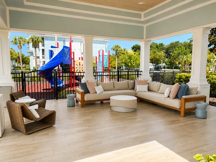 Chic outdoor lounge area with modern seating, elegant decor, and vibrant playground view, perfect for relaxation and family enjoyment.