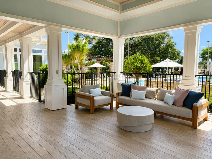 Charming outdoor patio with cozy seating, surrounded by lush greenery and pool views for a serene retreat.