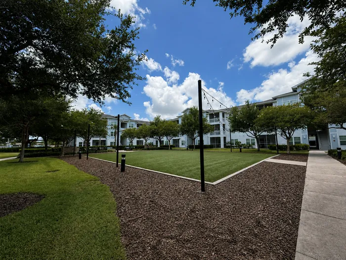 Charming apartment complex surrounded by lush greenery and open sky, offering a serene and inviting outdoor space.