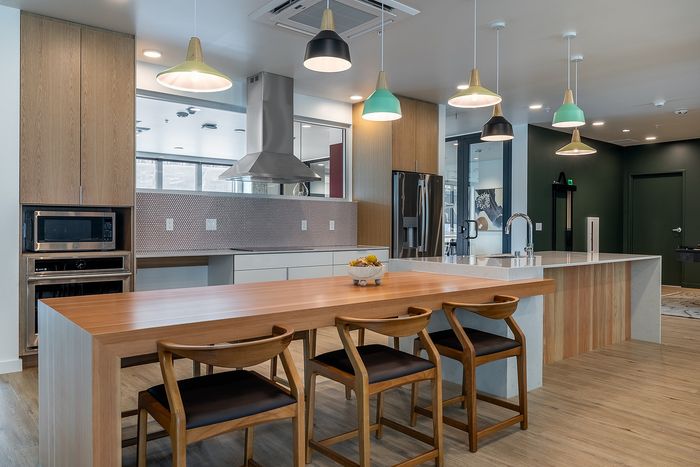 Modern, spacious kitchen with sleek wooden cabinetry, large island and chic pendant lighting, perfect for entertaining.
