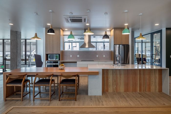 Modern open-concept kitchen with sleek wooden dining table, stylish pendant lighting, and stainless steel appliances.