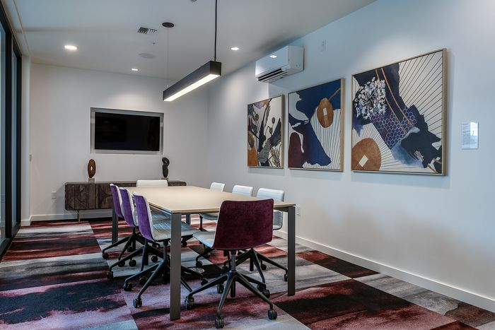 Modern conference room with vibrant decor, featuring stylish art pieces and a sleek meeting table with comfortable chairs.