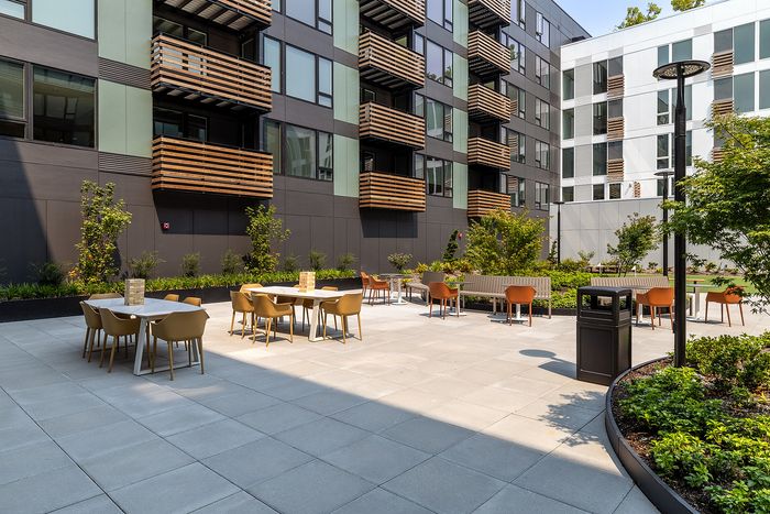 Modern apartment patio with stylish outdoor seating and lush green landscaping, perfect for relaxation and social gatherings.