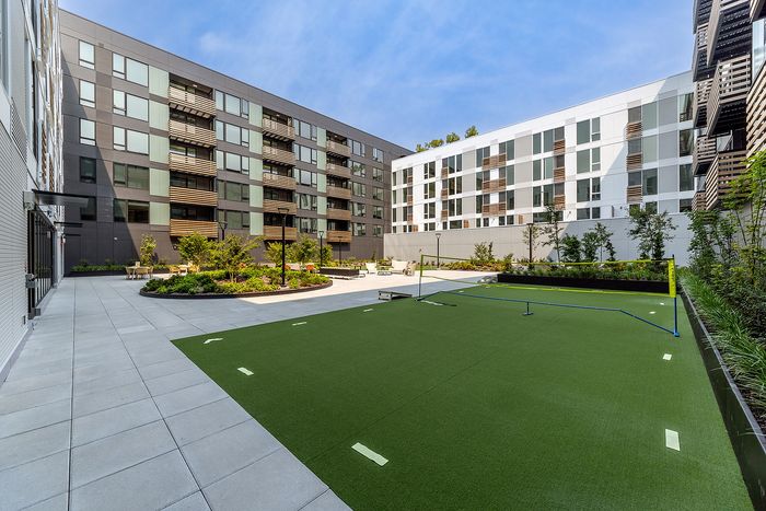 Modern apartment courtyard featuring a lush green space with a leisure area and elegant surrounding buildings.