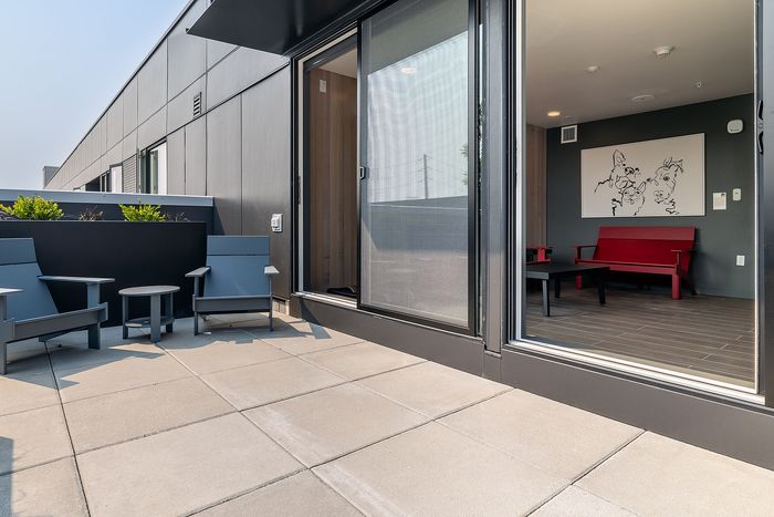 Chic urban apartment balcony featuring modern patio seating and sliding glass doors opening to a stylish interior.