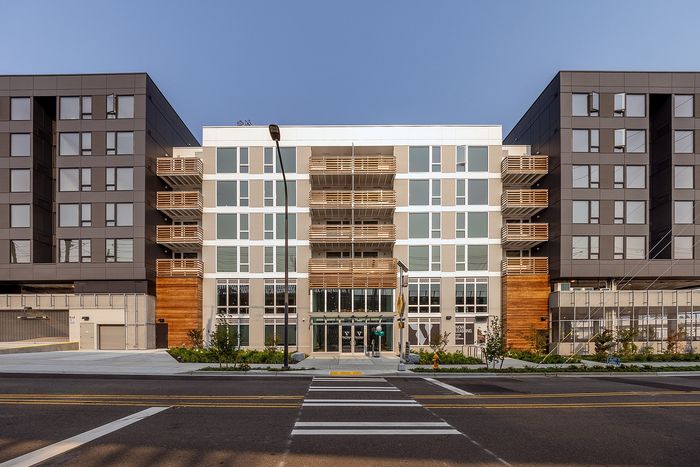 Modern apartment building with sleek design, large windows, and inviting entrance, set against a clear blue sky.