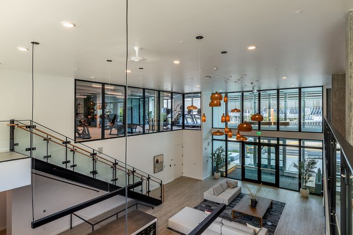 Modern lobby with sleek glass staircase, plush seating, and warm pendant lighting, offering a welcoming and stylish atmosphere.