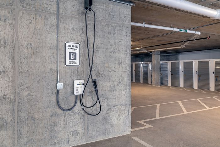 Modern parking area with an electric car charging station and secure storage units, offering convenience and sustainability for residents.