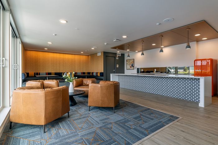 Modern lounge area with stylish leather seating, chic pendant lighting, and a geometric-patterned bar, complemented by vibrant decor and a sleek wooden floor.