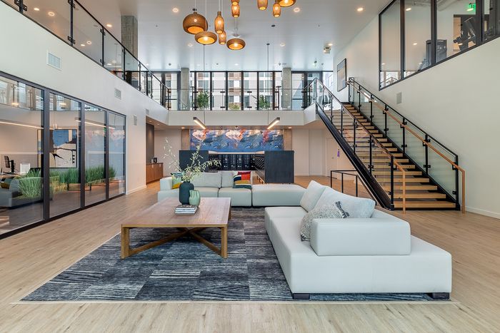 Luxurious modern lounge area featuring chic seating, elegant wooden staircase, and stylish lighting, perfect for relaxation and social gatherings.