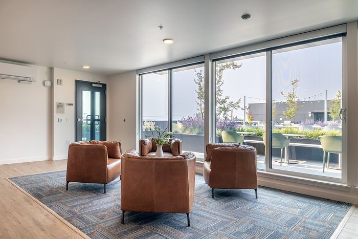 Modern living space with plush leather chairs and large windows overlooking a beautifully landscaped terrace.