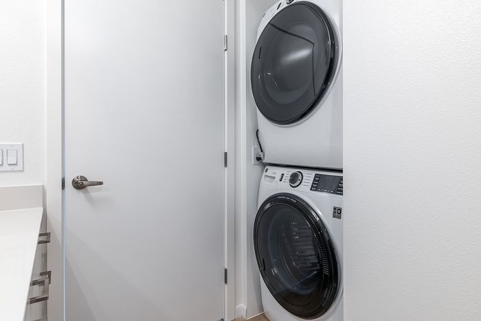 Modern apartment with stacked washer and dryer in a sleek, bright laundry nook.