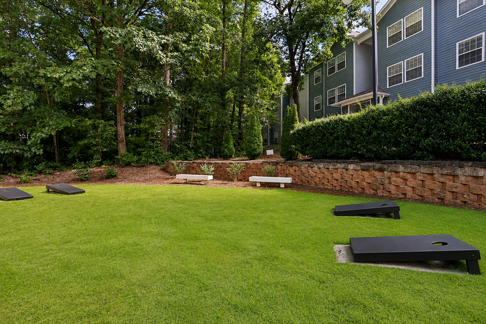 Cornhole area with landscaped social lawn and seating at Avana TownPark in Kennesaw, GA