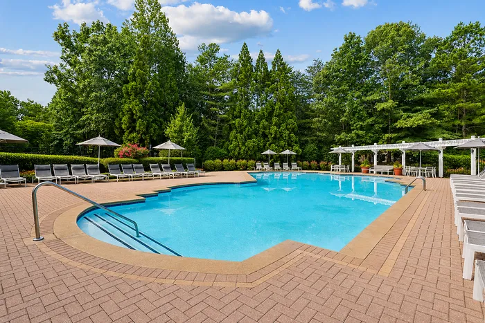 Pool deck with lounge chairs and shaded umbrellas at Avana TownPark apartments in Kennesaw, GA