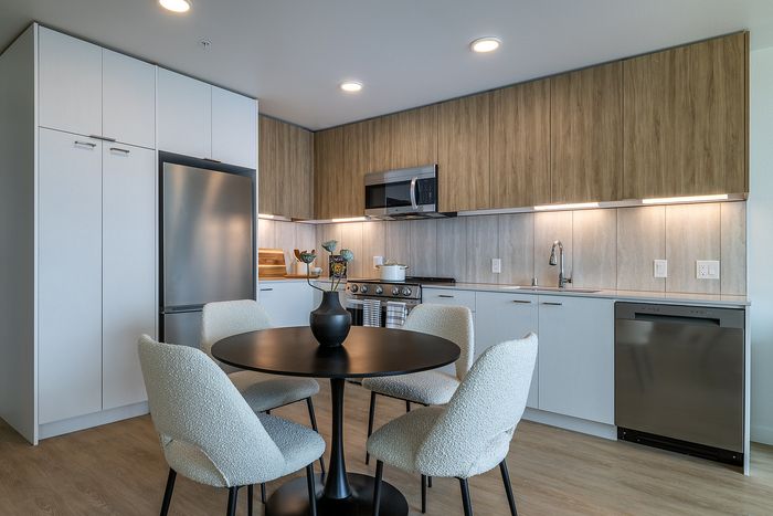Elegant modern kitchen featuring sleek cabinetry, stainless steel appliances, and a chic round dining table with plush chairs.