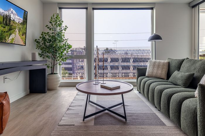 Bright and inviting living room featuring plush green sofa, modern coffee table, and floor-to-ceiling windows offering a stunning view.