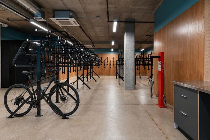 Modern apartment bike storage room with sleek racks, concrete flooring, and built-in repair station, offering convenience and style.
