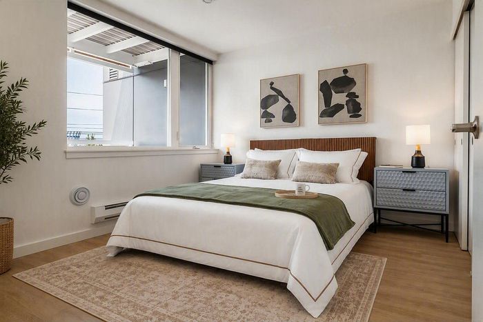 Chic bedroom with modern decor, large window, and cozy lighting accentuating warm wooden floors.