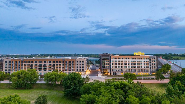 Elegant residential building with a scenic view of lush greenery and a tranquil river backdrop, featuring modern architecture and ample natural light.