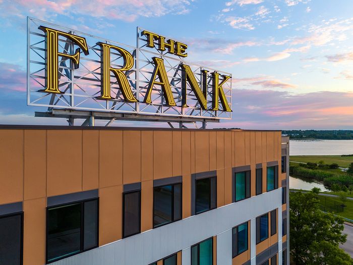 Chic apartment building with stunning rooftop signage, overlooking serene waterfront views at sunset.