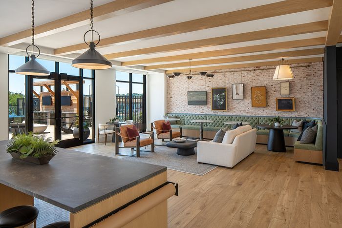 Modern open-concept living space with stylish wooden beam ceiling, elegant furnishings, and abundant natural light from large windows.