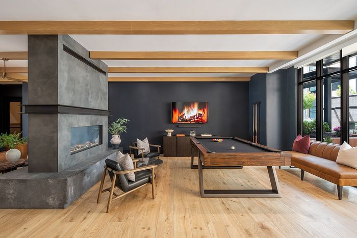 Luxurious lounge area featuring a modern fireplace, elegant pool table, chic seating arrangement, and large windows offering abundant natural light.
