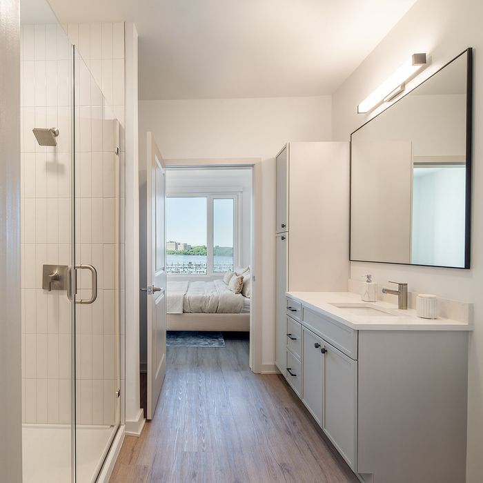Elegant bathroom view with modern fixtures leading to a bedroom with stunning window view of cityscape.