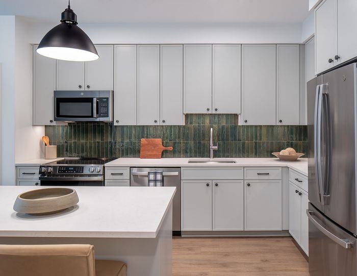 Modern kitchen with sleek white cabinetry, stainless steel appliances, and stylish pendant lighting.