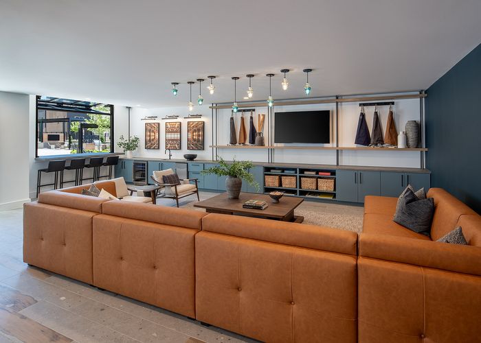 Contemporary living room with a sleek leather couch, elegant pendant lighting, and stylish open shelving, offering a chic and inviting atmosphere.