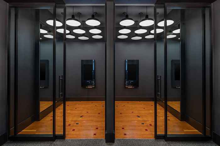 Modern apartment entrance featuring elegant glass doors, warm wood flooring, and stylish overhead lighting.