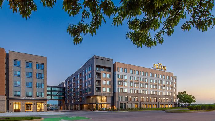Modern apartment complex with sleek architecture and large windows under a clear blue sky, perfect for urban living.