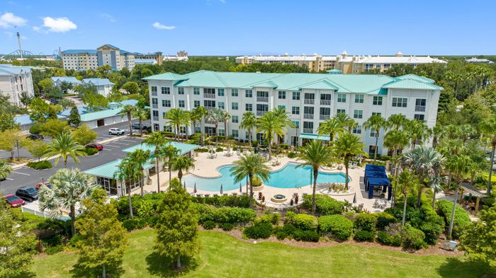 Beautiful resort-style apartment complex with lush landscaping, sparkling pool, and modern architecture, perfect for luxurious living.