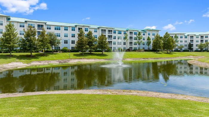 Beautiful residential building with a serene pond, lush greenery, and picturesque fountain, offering tranquil living.