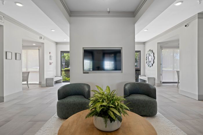 Modern lounge area with elegant seating, a flat-screen TV, and abundant natural light, perfect for relaxation and gatherings.