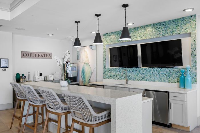 Chic community coffee bar with modern decor, featuring a sleek countertop, stylish seating, and vibrant mosaic backsplash.