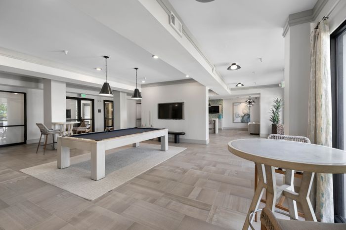Modern communal space featuring a sleek pool table, stylish lighting, and contemporary seating for leisure and socializing.