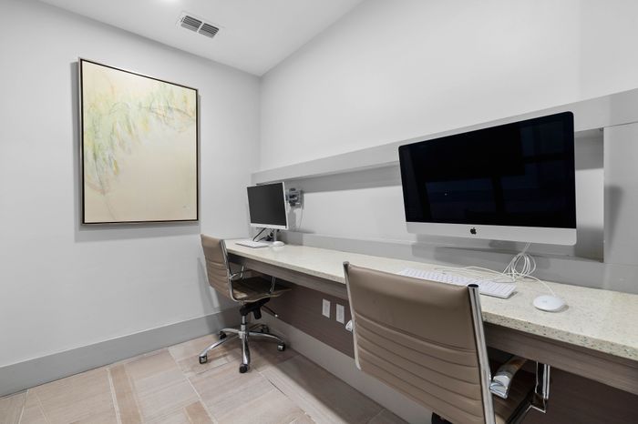 Modern office space with sleek minimalist design, featuring dual computer workstations and contemporary art.