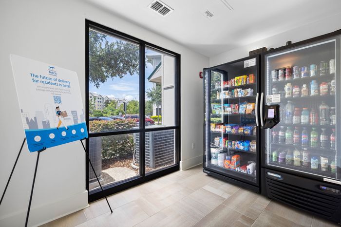 Modern apartment lobby featuring a convenient vending area with a variety of snacks and drinks next to a large window with a scenic view.