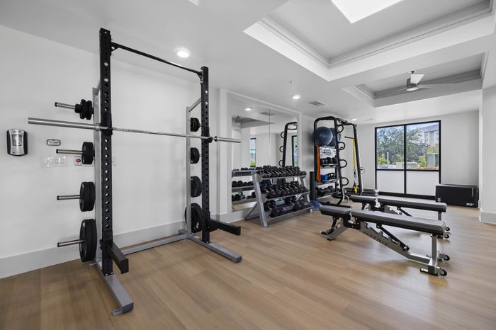 Modern fitness center with state-of-the-art equipment, including weights and workout benches, in a bright space with natural light.