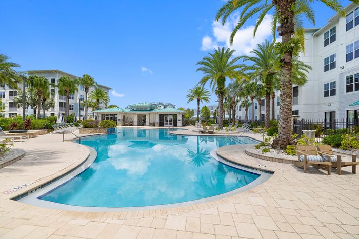 Luxurious apartment complex featuring a pristine resort-style pool surrounded by palm trees and modern lounge areas, offering ultimate relaxation and elegance.