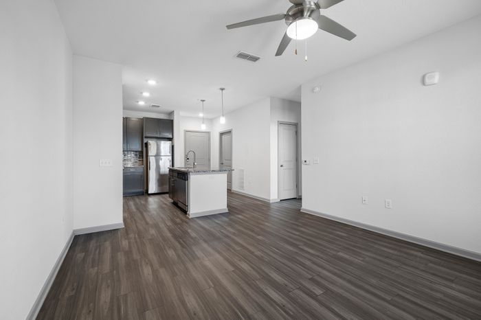 Modern apartment kitchen with stainless steel appliances, elegant grey cabinetry, and sleek wood flooring.