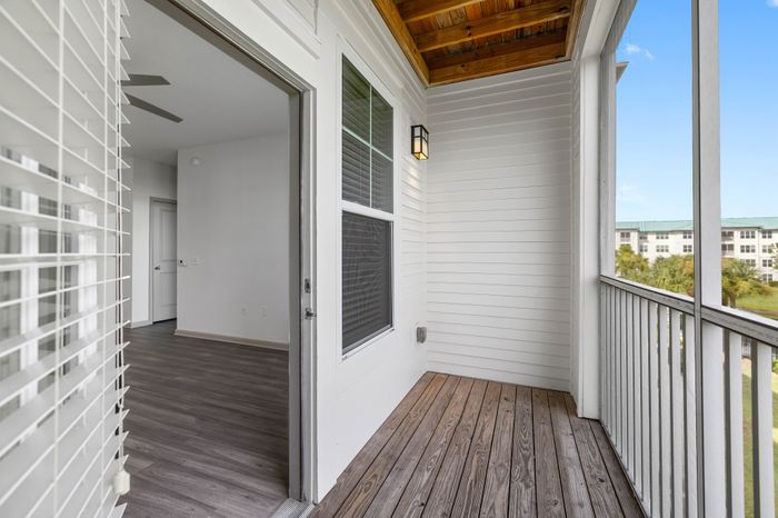 Inviting apartment balcony with wooden flooring, modern railing, and a bright interior view, ideal for relaxation and enjoying scenic surroundings.