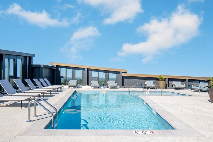 Luxurious rooftop pool oasis with modern lounge chairs and panoramic city views.