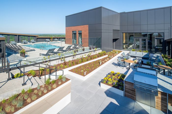 Contemporary rooftop oasis featuring a sleek pool, stylish lounge chairs, vibrant landscaped gardens, and modern outdoor seating area.