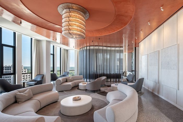 Luxurious open-concept living area with elegant curved sofas, panoramic city views, and a stunning sculptural ceiling light.