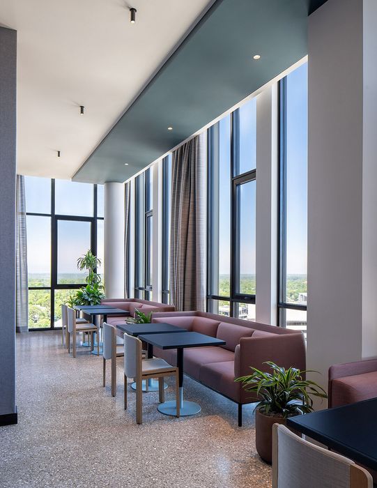 Elegant high-rise dining area with panoramic windows, modern seating, and lush greenery offering stunning views.