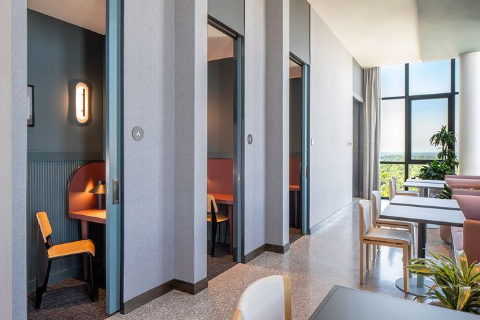 Contemporary shared workspace with private booths, stylish seating, and floor-to-ceiling windows offering scenic views.